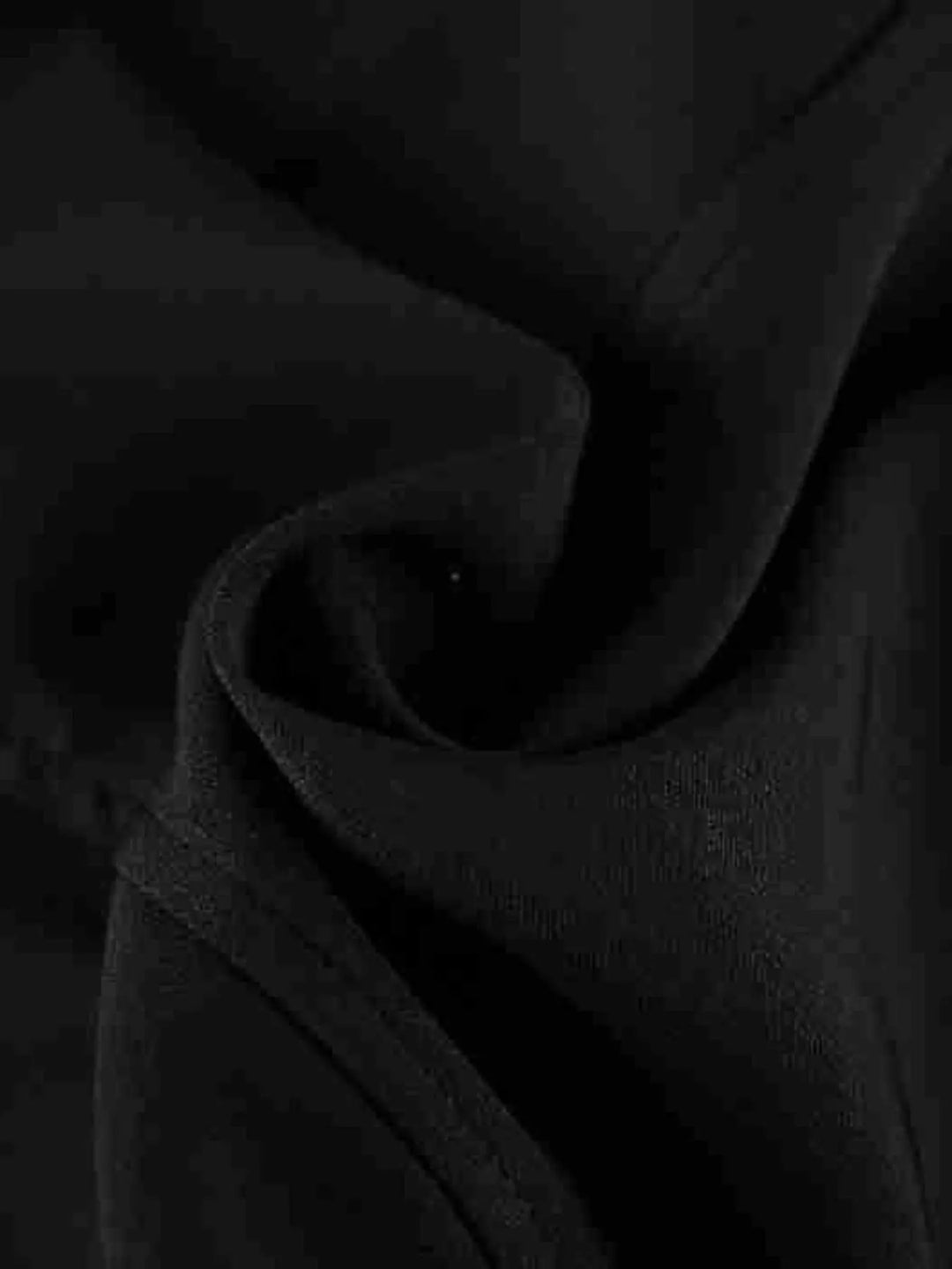 Black dress fabric folds close-up showing the smooth matte texture