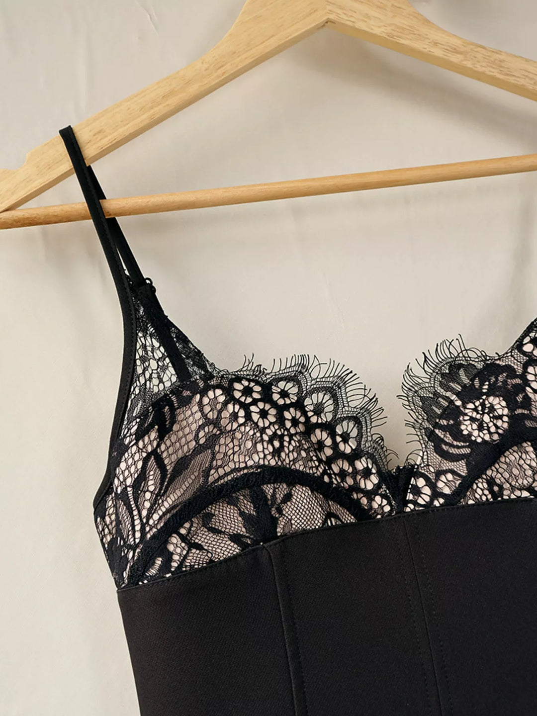 Close-up of the lace cup neckline and straps on the black dress, hanging