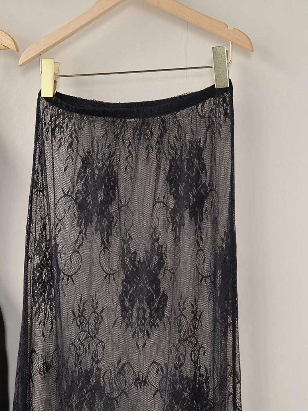 Black lace overlay skirt hanging with an elastic waistband, front