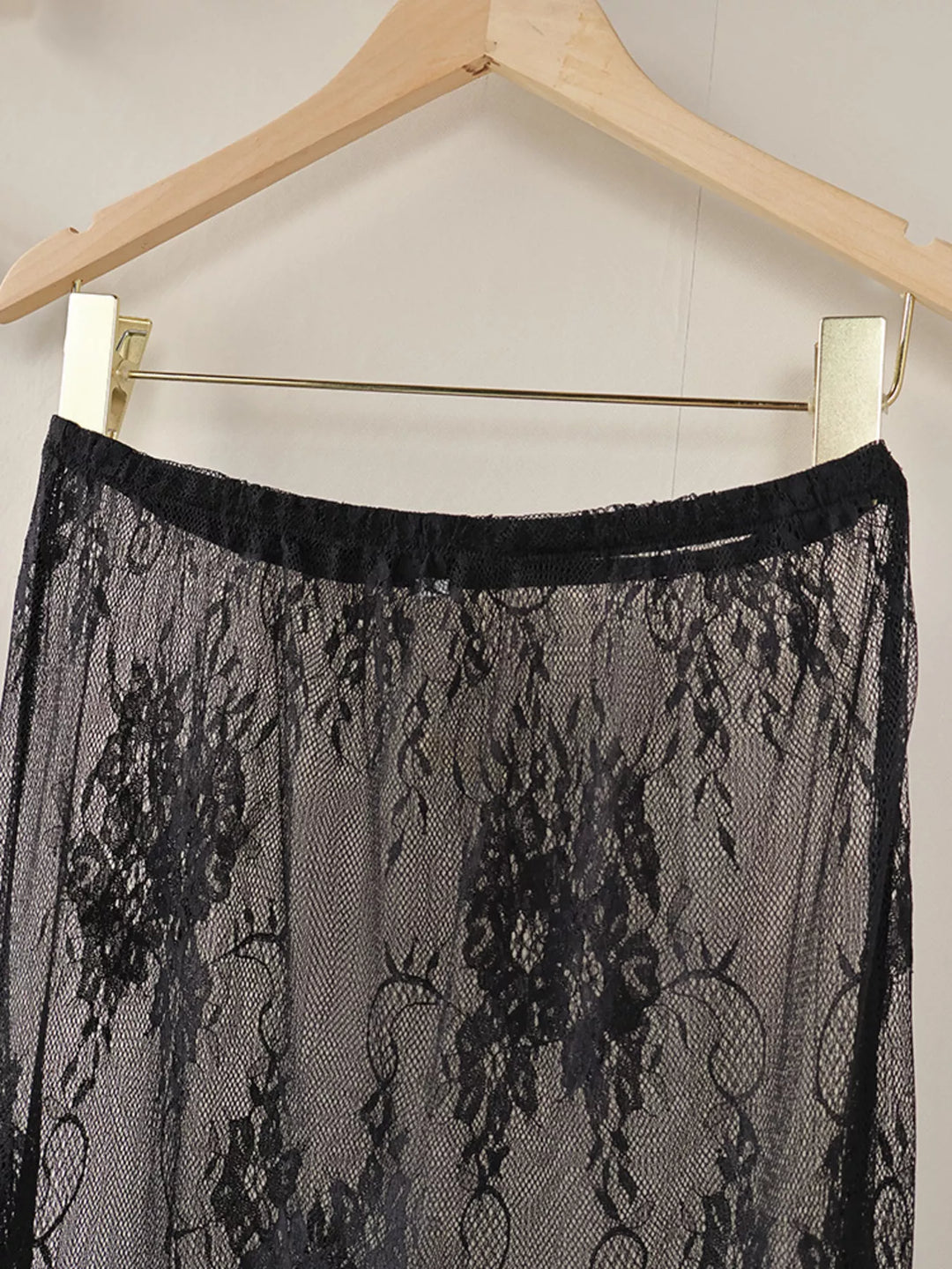 Black sheer floral lace overlay skirt on a hanger, upper section