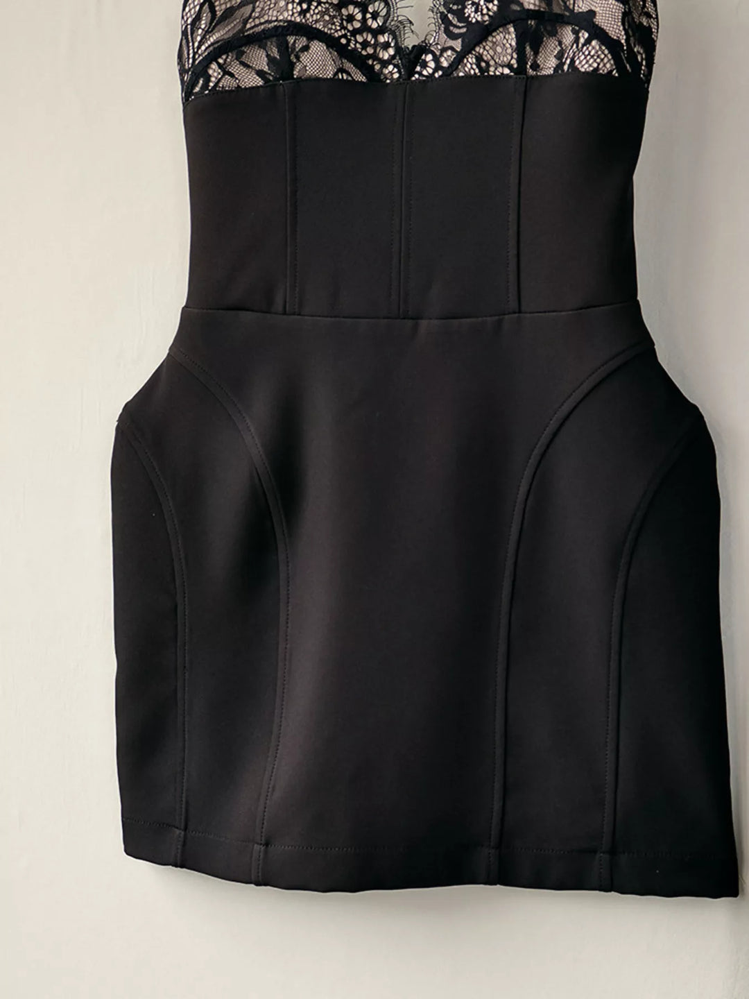Black mini dress front laid flat with the structured skirt and lace bodice
