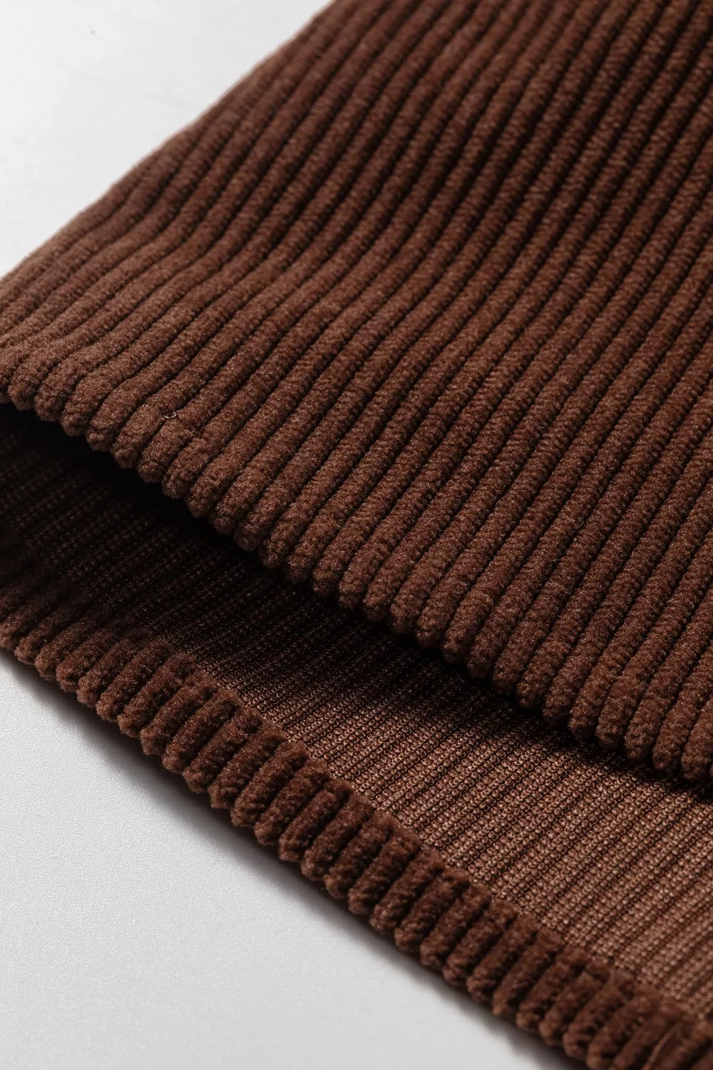 Close-up of the corduroy ribs where the dark brown fabric folds at the hem
