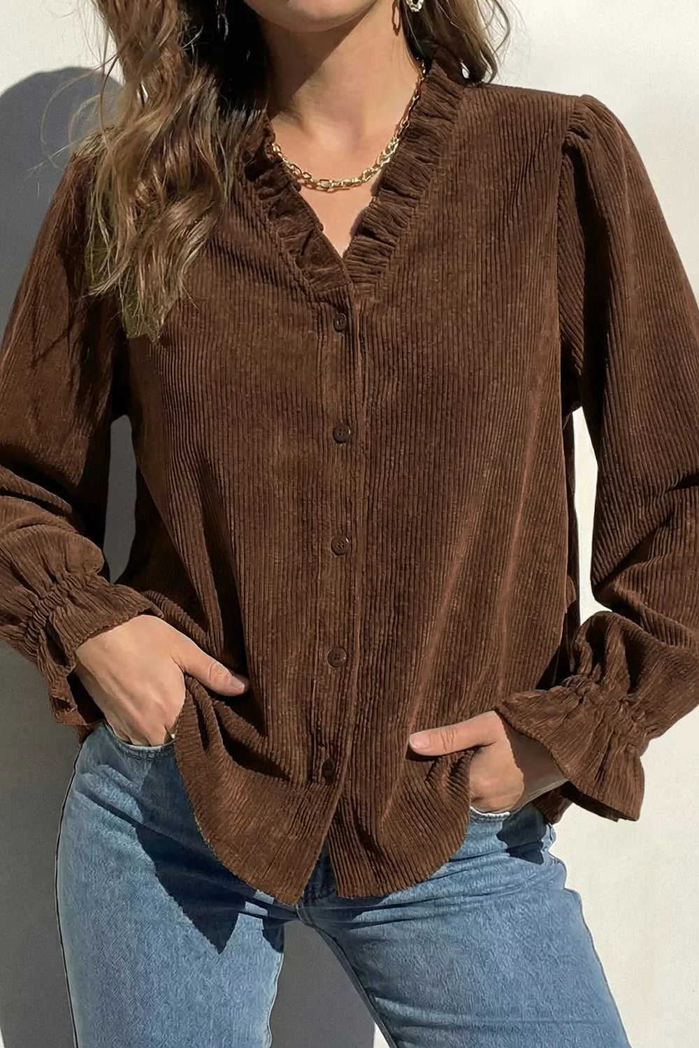 Women's corduroy shirt in dark brown with ruffle neck, front view with hands in pockets