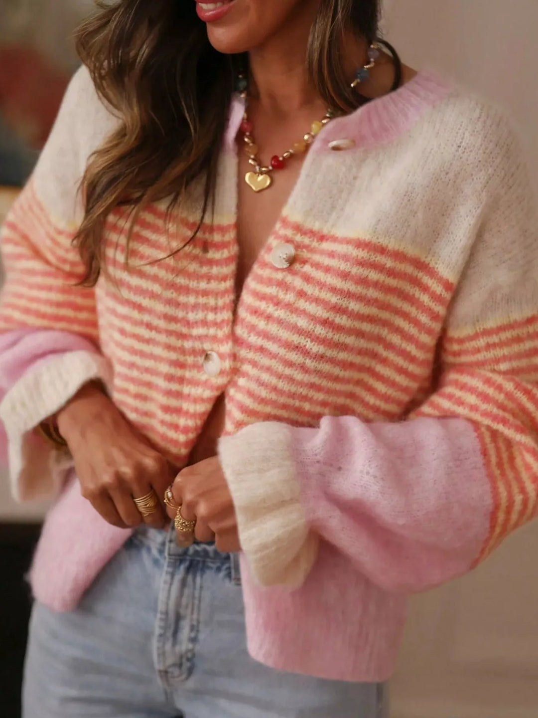 Pink striped cropped cardigan buttoned up, worn with light wash jeans