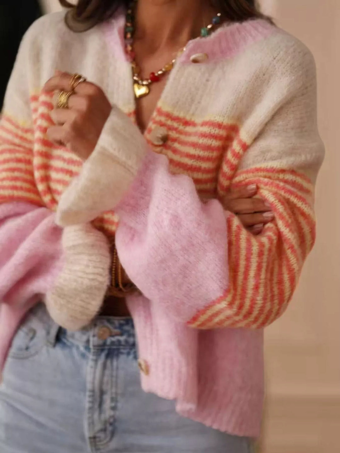 Pink color block cardigan with ruffled cuffs, hands holding the open front