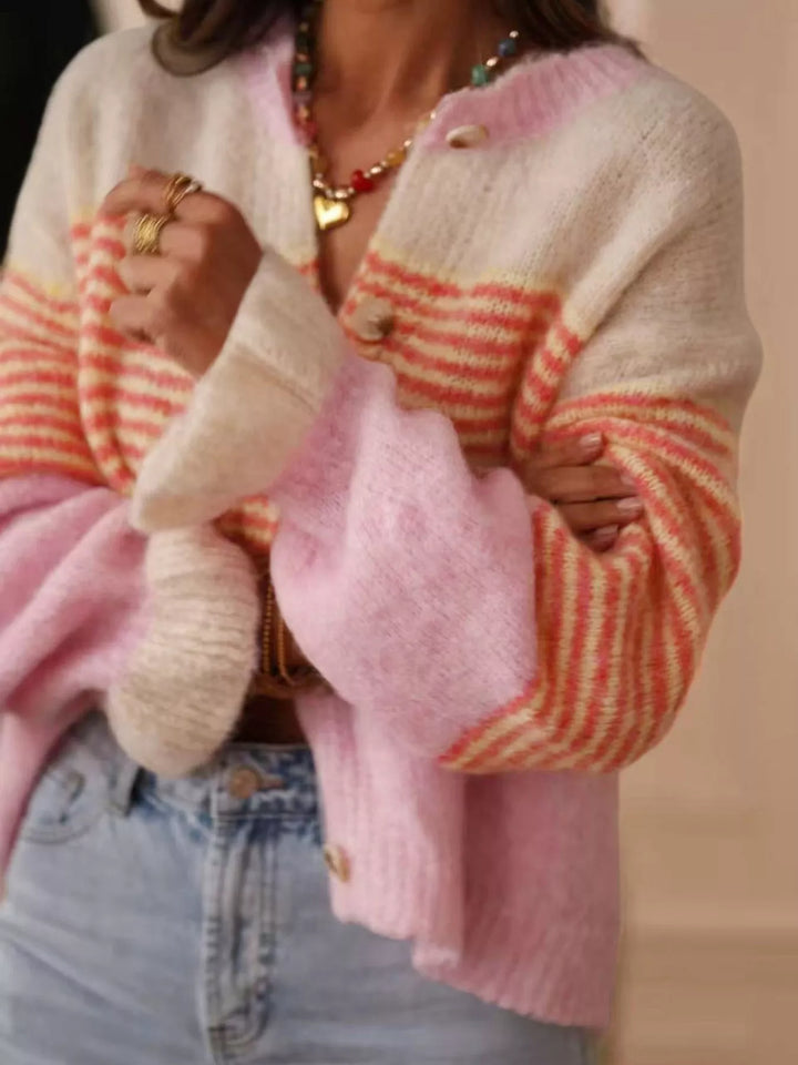 Pink color block cardigan with ruffled cuffs, hands holding the open front