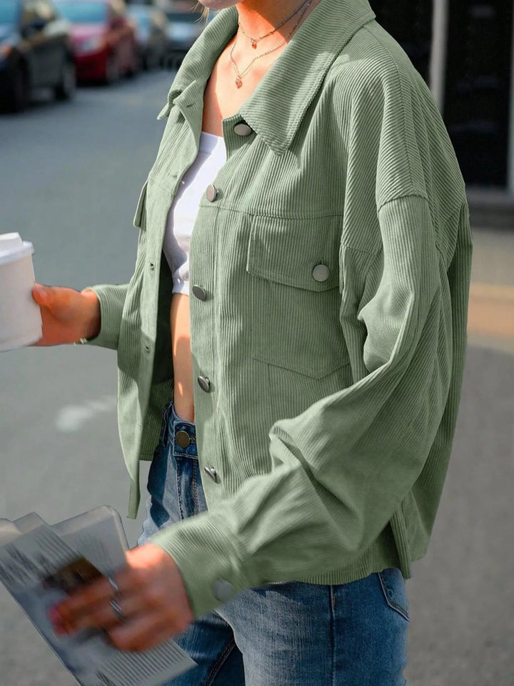 Sage green cropped shirt jacket in a walking street pose