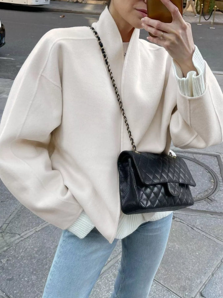 Ivory open front jacket styled with jeans and a quilted shoulder bag