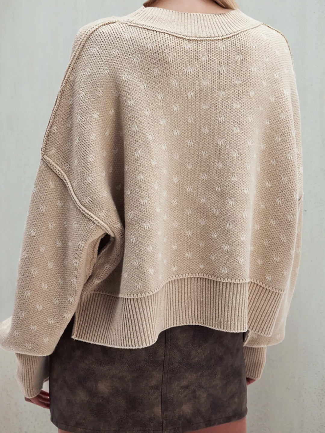 Back view of the beige heart pattern cropped sweater with side slit