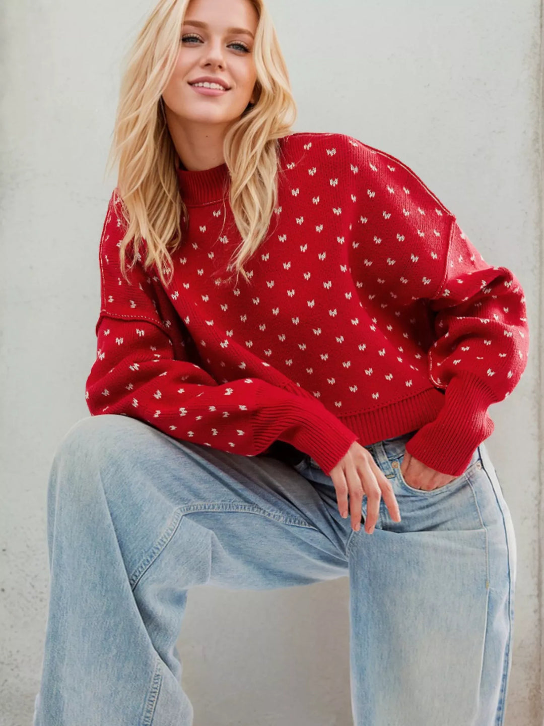 Red heart pattern sweater with a knee raised on a stool