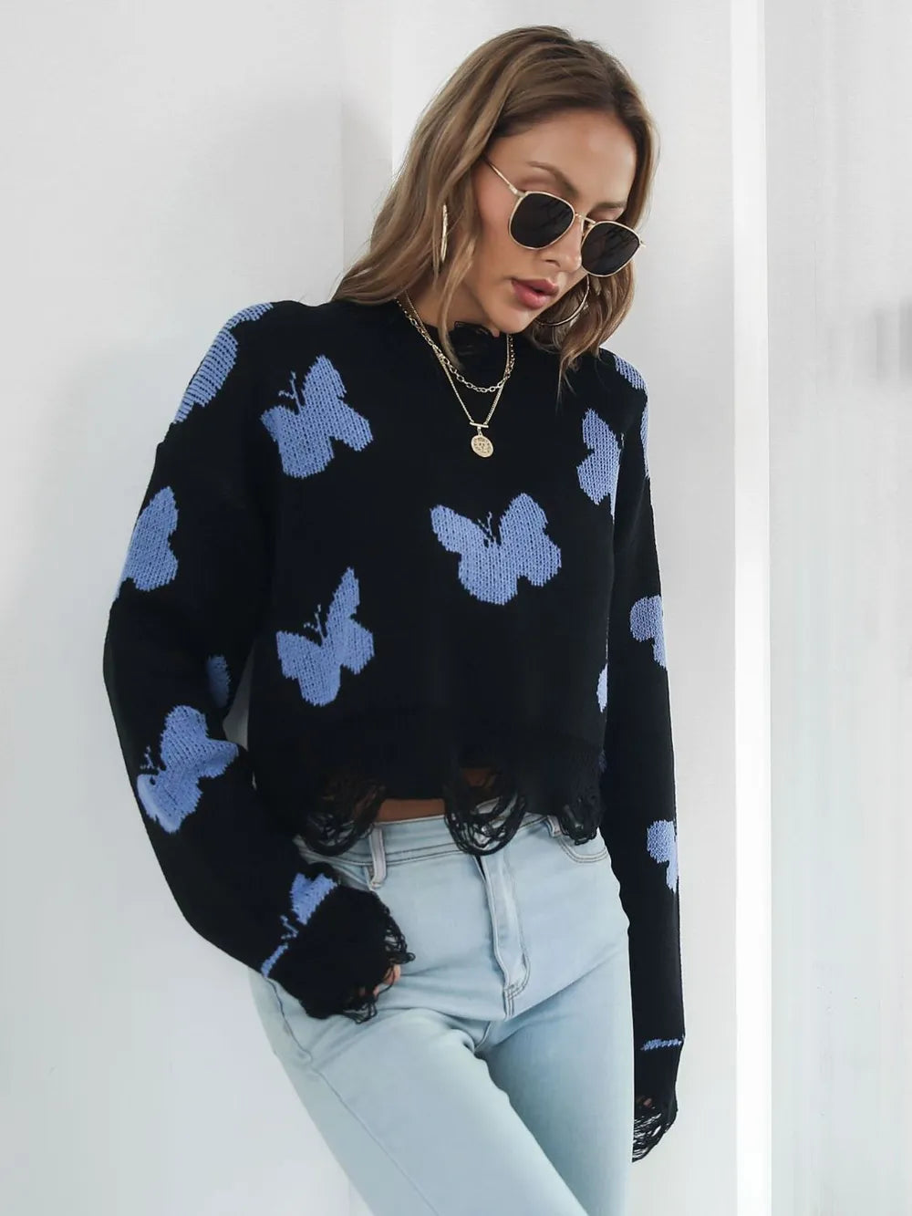 Black butterfly sweater worn with light wash jeans, front view