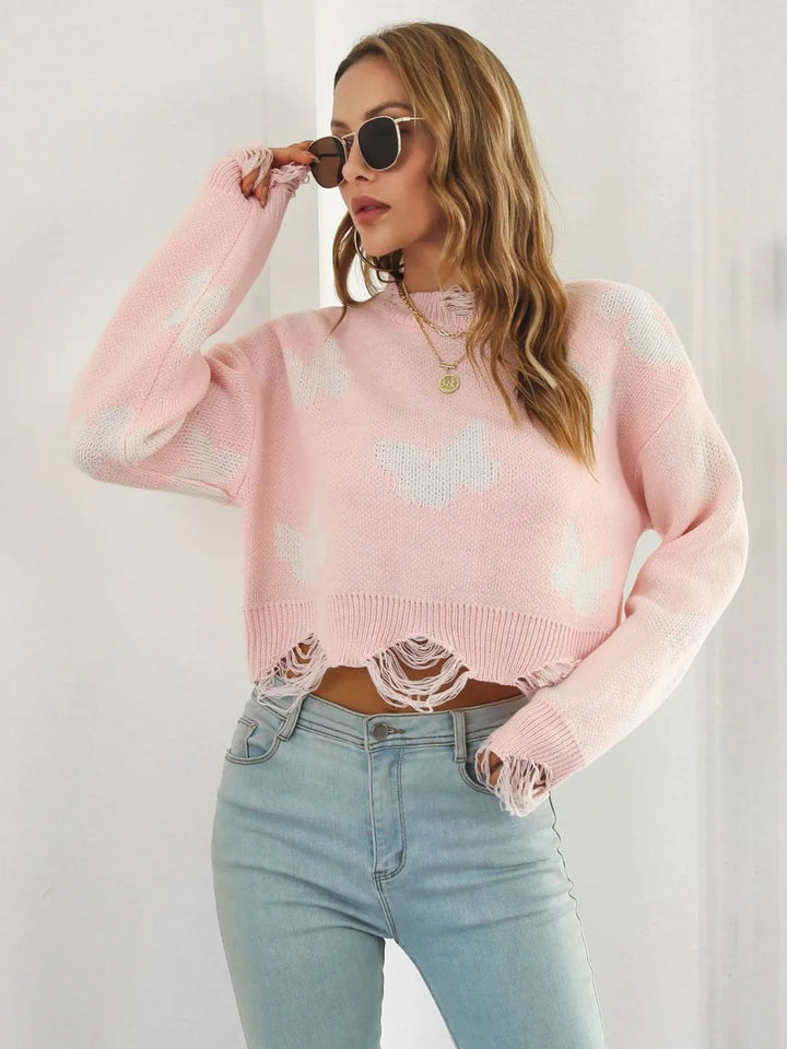 Blush pink cropped sweater with hand raised to sunglasses