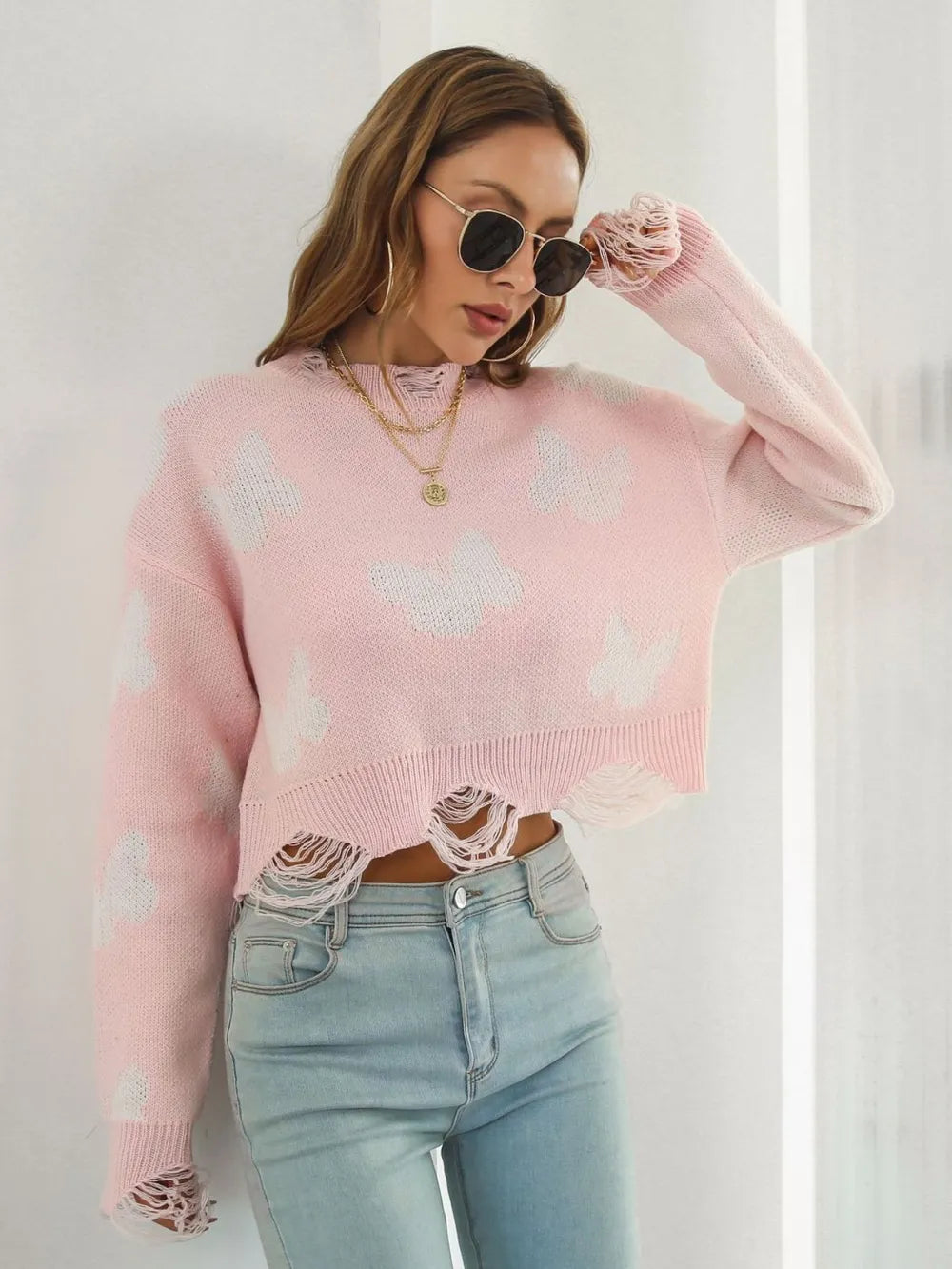 Blush pink butterfly sweater with sunglasses lowered, front view