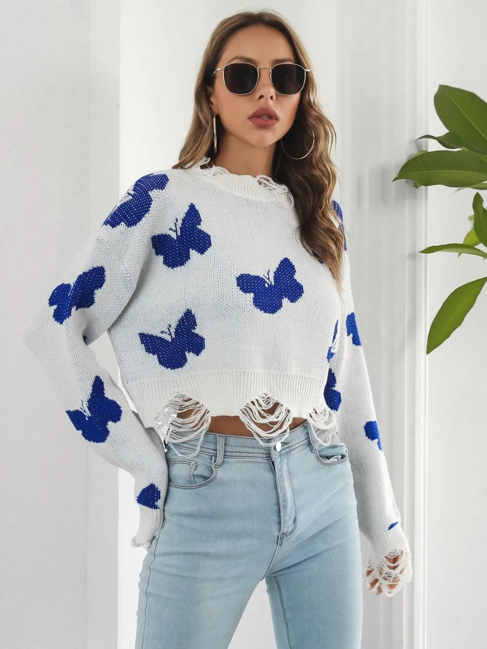 White crew neck cropped sweater with butterflies, hands on hips