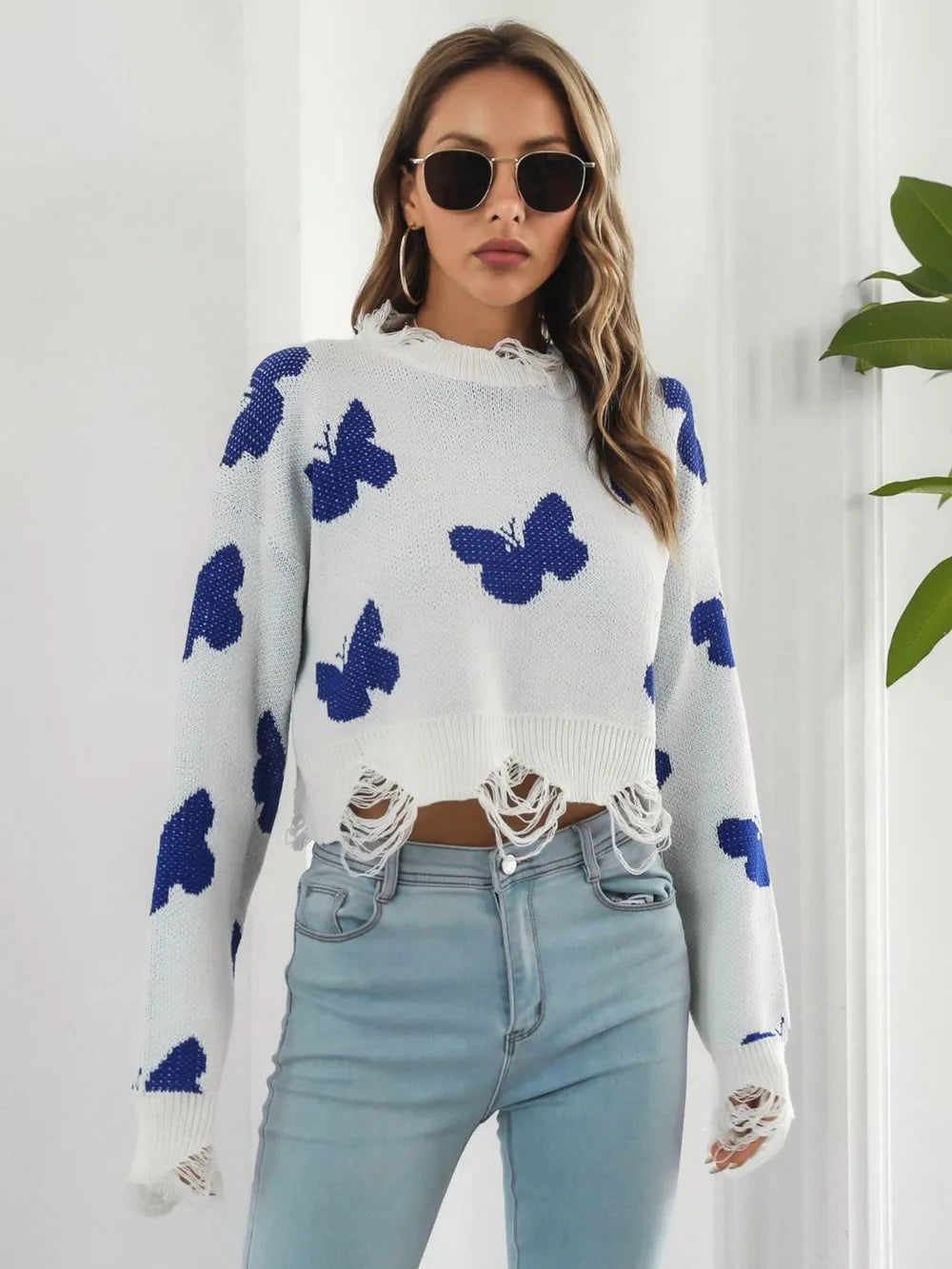 Front view of the white butterfly sweater with frayed hem and light jeans