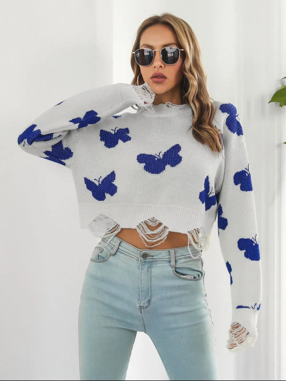 Women's cropped sweater in white with blue butterfly print and distressed hem