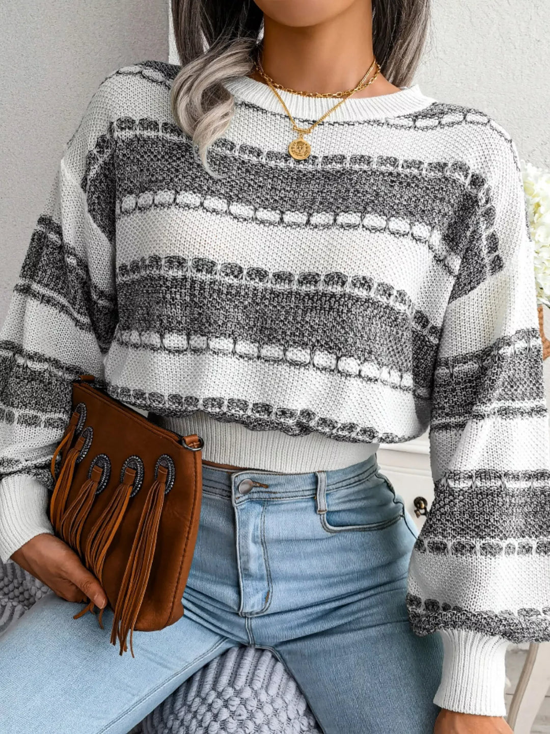 Dark gray striped sweater seated with a fringe clutch on the lap