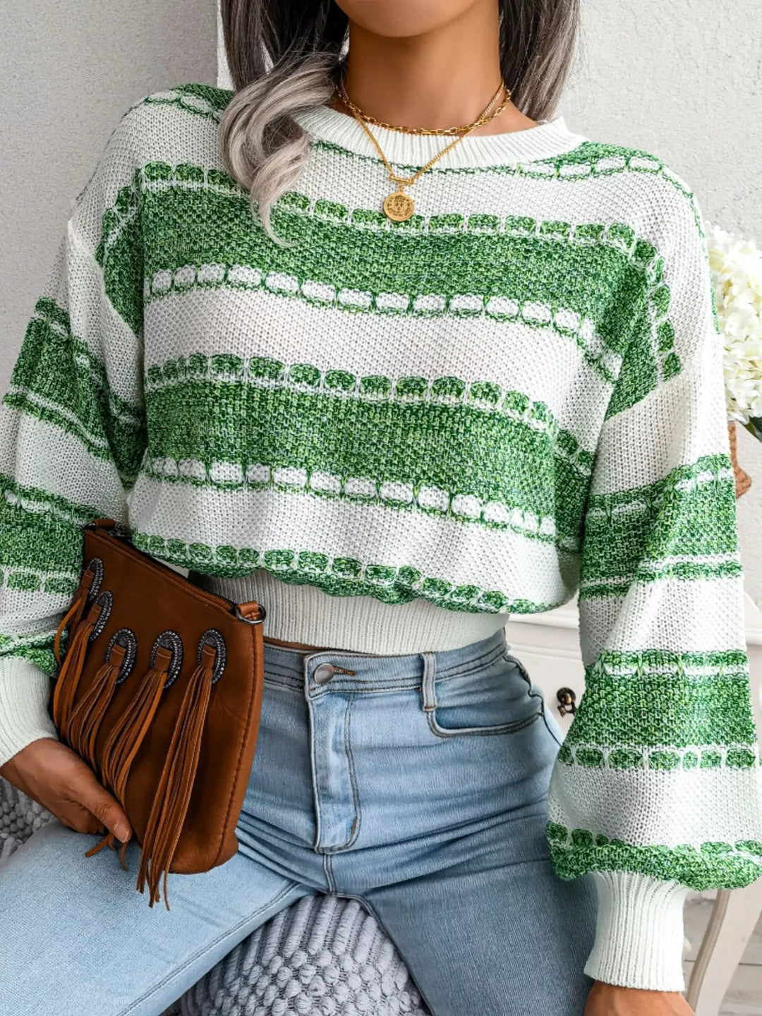 Green cropped crew neck sweater seated with a brown fringe clutch