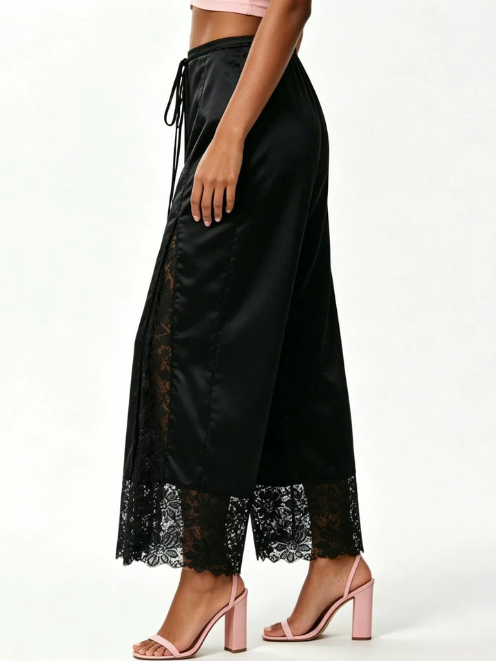 Side view of the black drawstring pants showing the gathered lace panel and pink heels