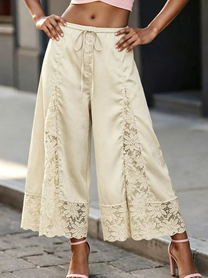 Champagne lace panel pants worn with a pink crop top and hands on hips