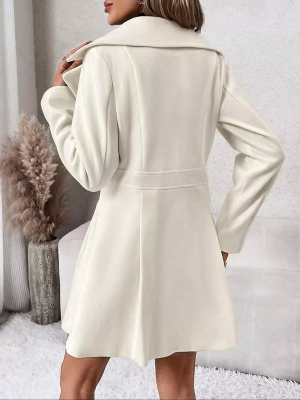 Back view of the ivory double breasted coat with fitted waist and flared skirt