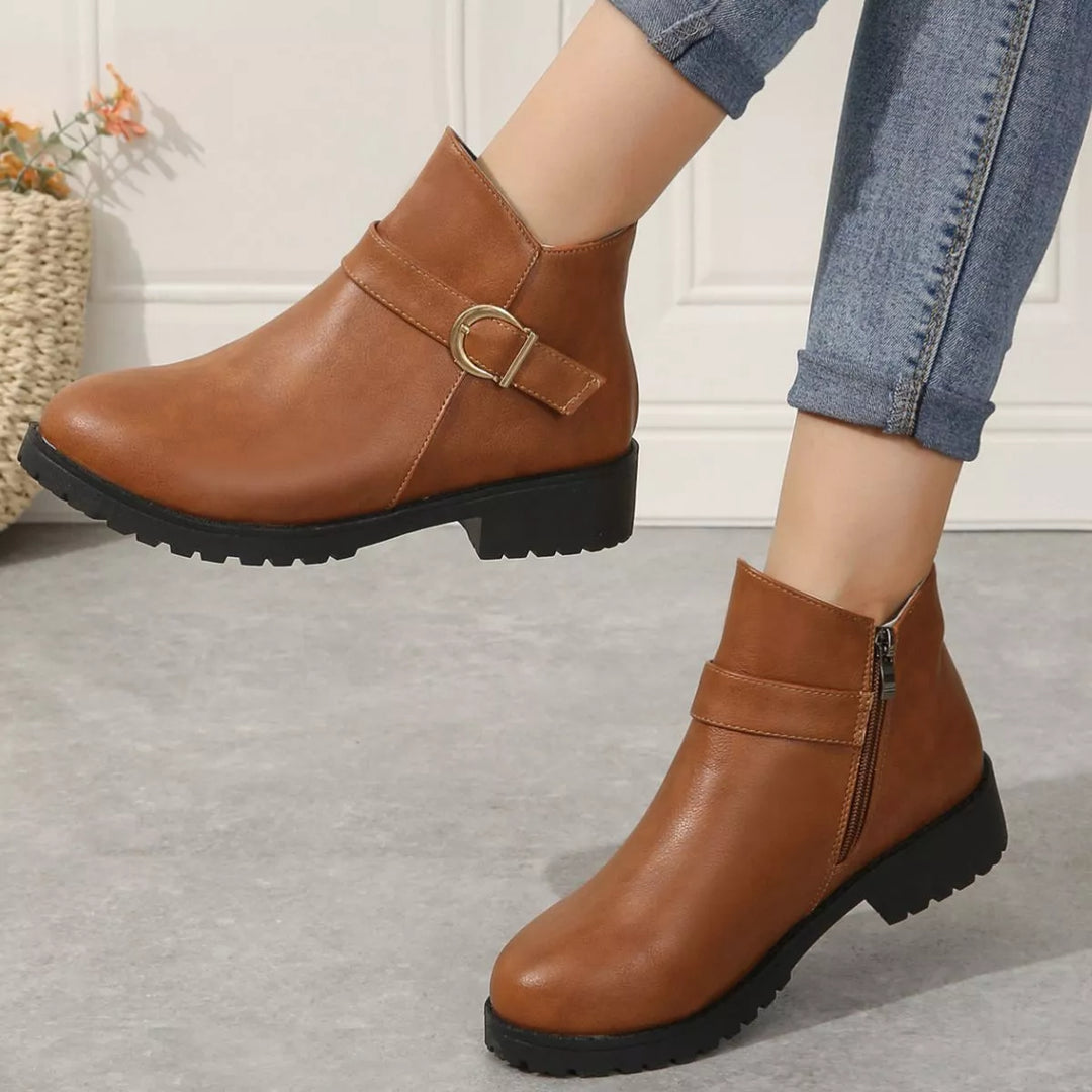 Cognac low block heel boots from the side, one foot resting on its toe