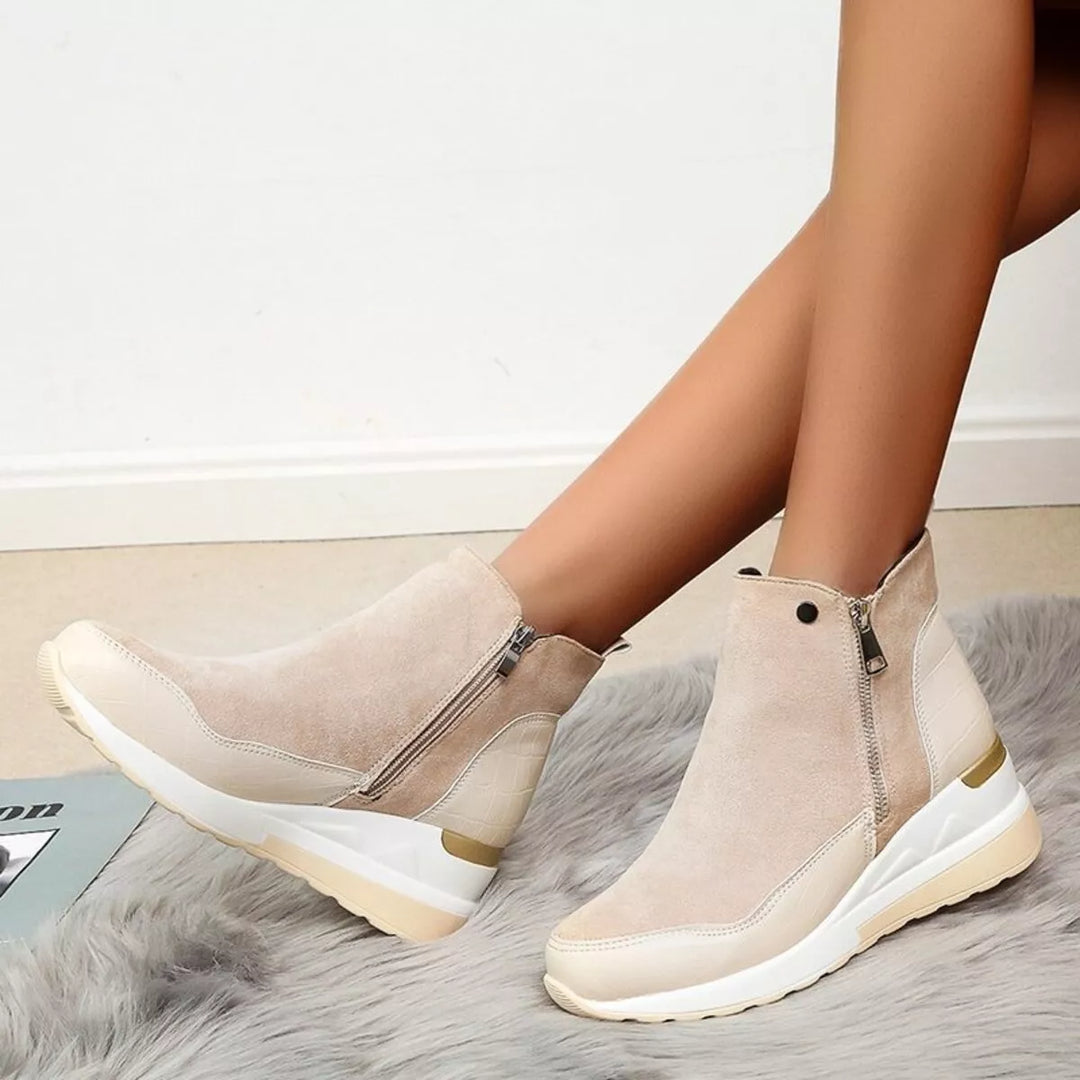 Beige wedge platform boots with side zip, worn with crossed legs