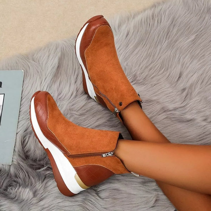 Cognac platform wedge boots worn with legs crossed, side zipper visible
