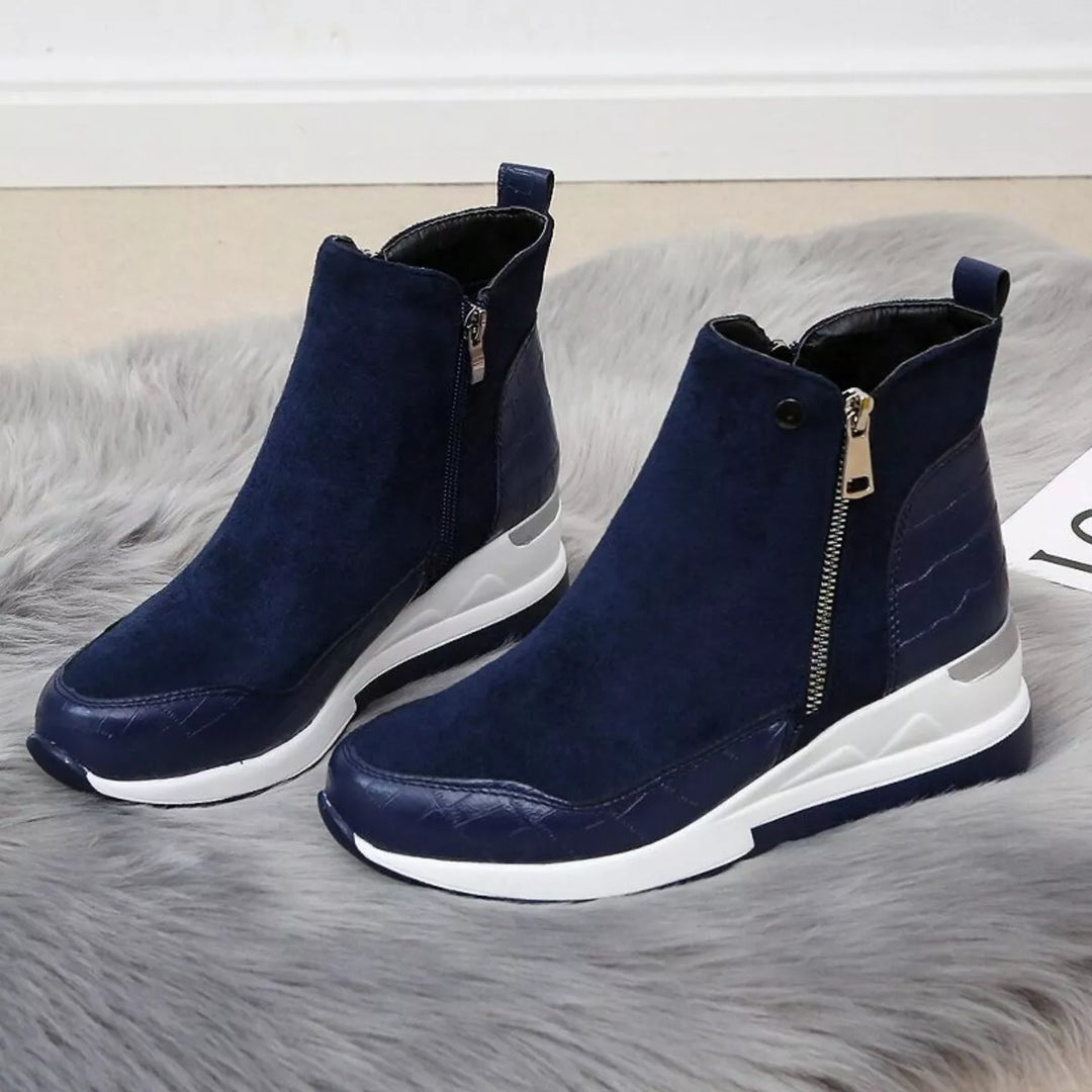 Pair of navy wedge boots with side zippers on a gray fur rug