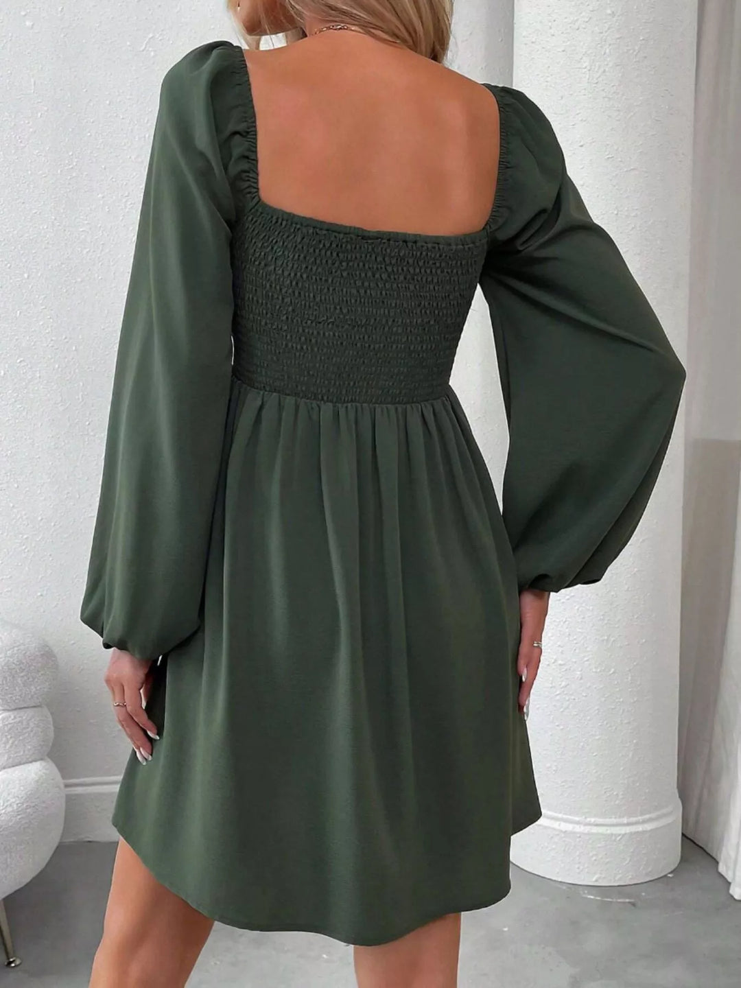 Army green mini dress worn on a model, showing the ruched smocked bodice