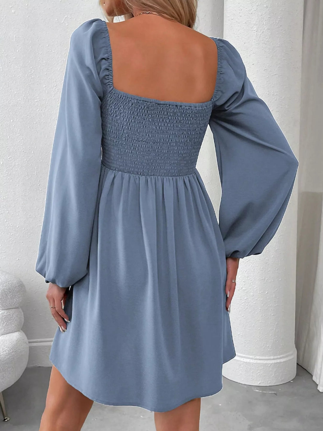 Blue mini dress worn on a model, showing the ruched smocked bodice