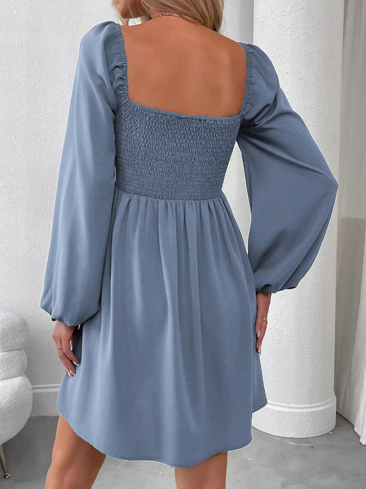 Blue mini dress worn on a model, showing the ruched smocked bodice