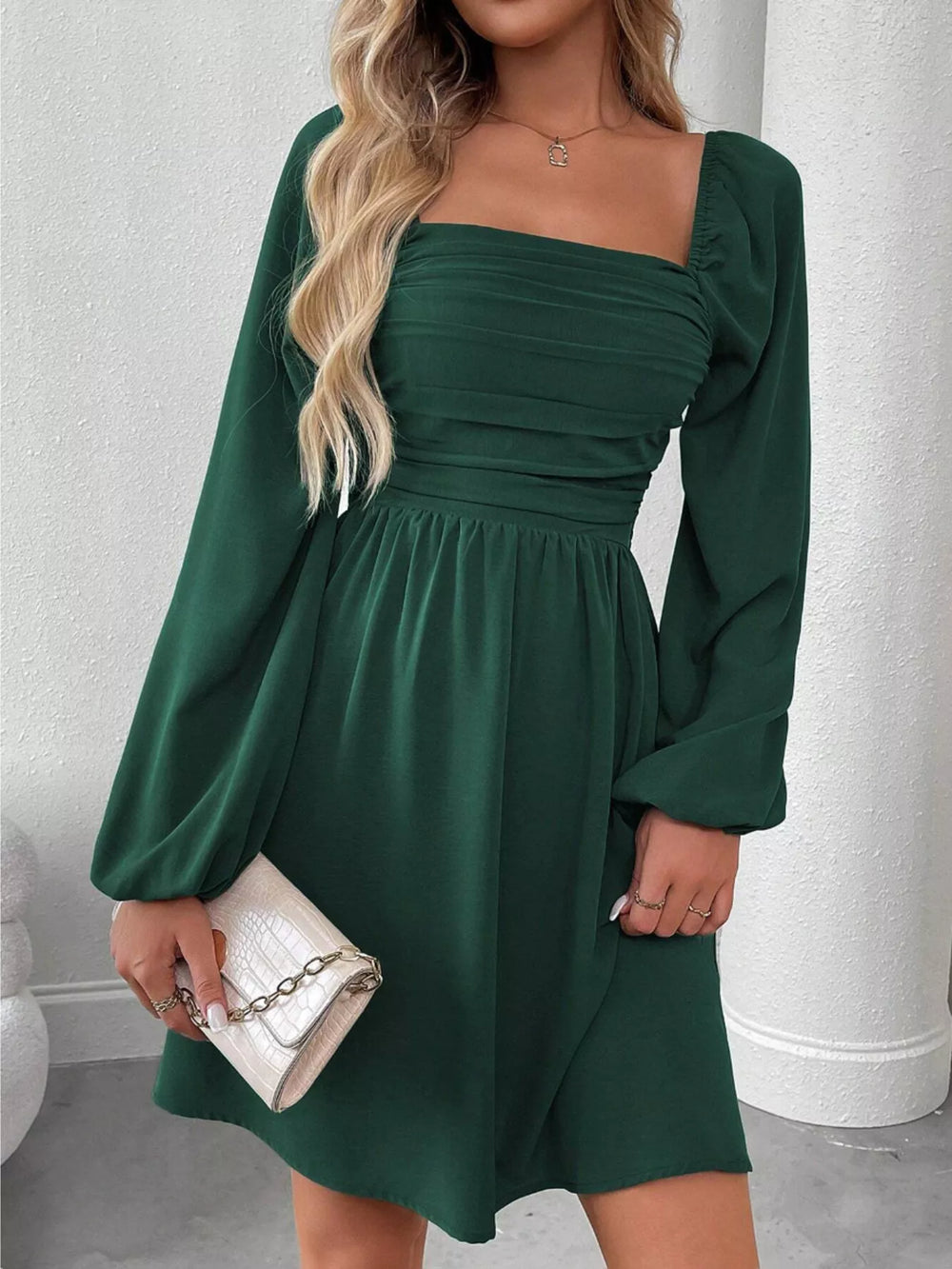 Dark green mini dress worn on a model, showing the square neckline