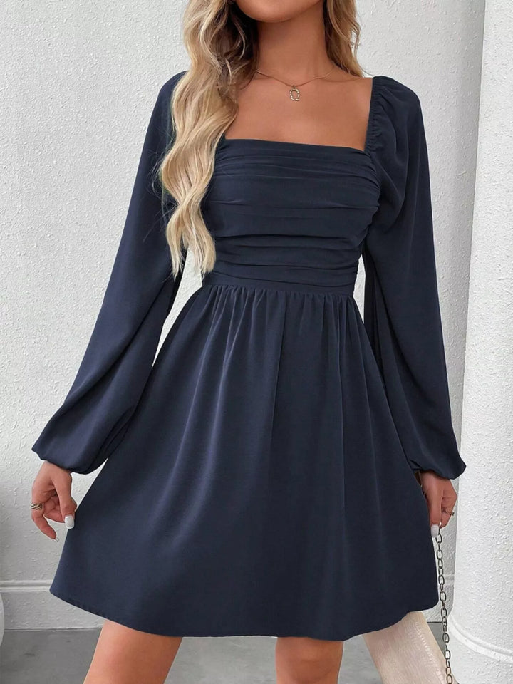 Navy blue mini dress worn on a model, showing the square neckline