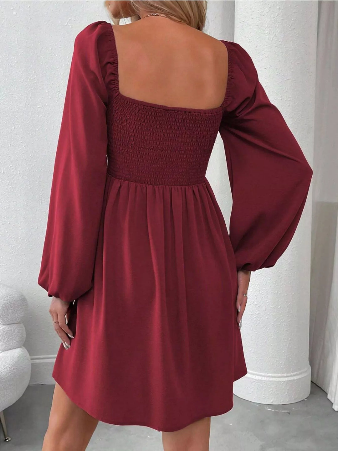 Wine red mini dress worn on a model, showing the ruched smocked bodice