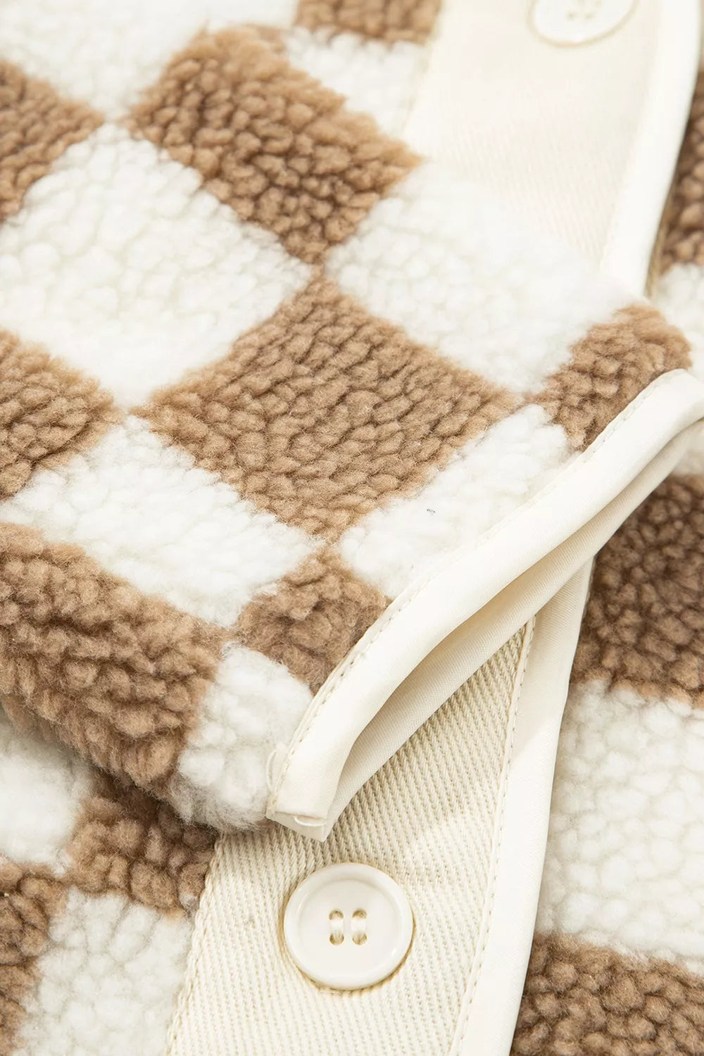 Close-up of the plush checkerboard texture with button and cream edge trim