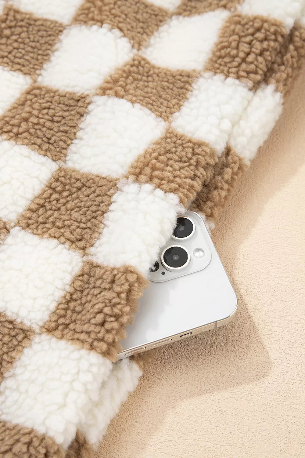 Pocket of the checkerboard jacket holding a phone, showing the plush pattern