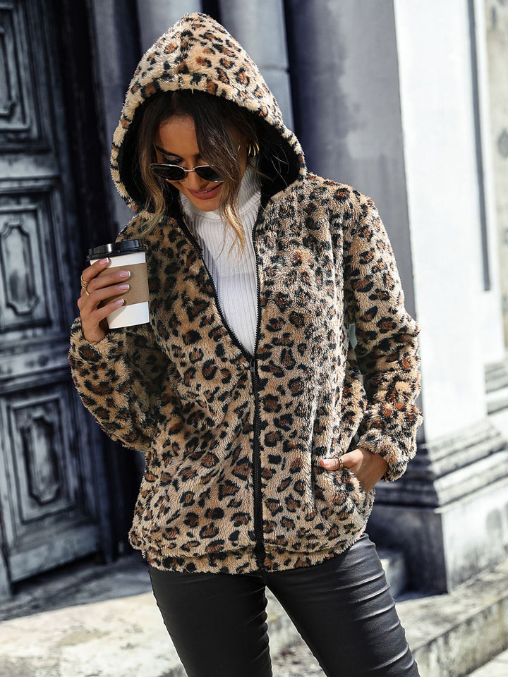 Women's fall jacket in fuzzy leopard print with hood and front zip, holding coffee