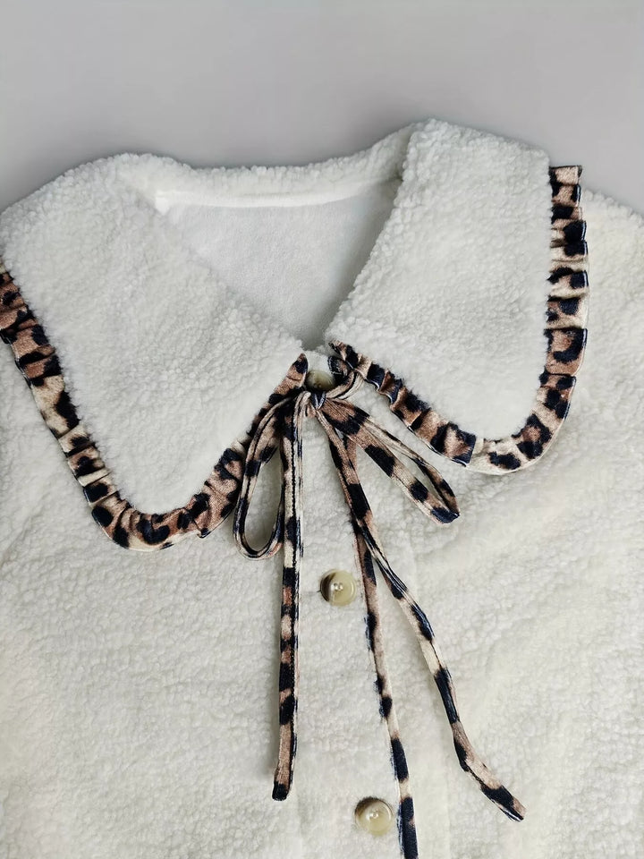 Close-up of cream plush collar with leopard trim bow tie and buttons