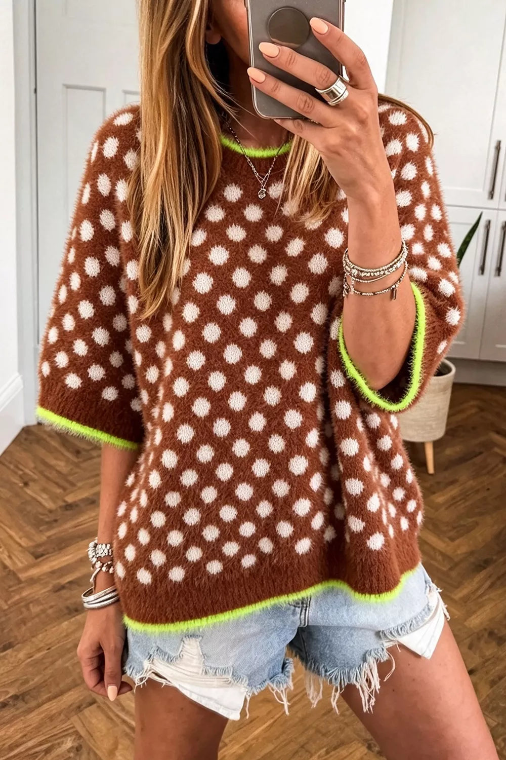 Women's brown fall sweater with polka dots and round neck, styled with denim shorts