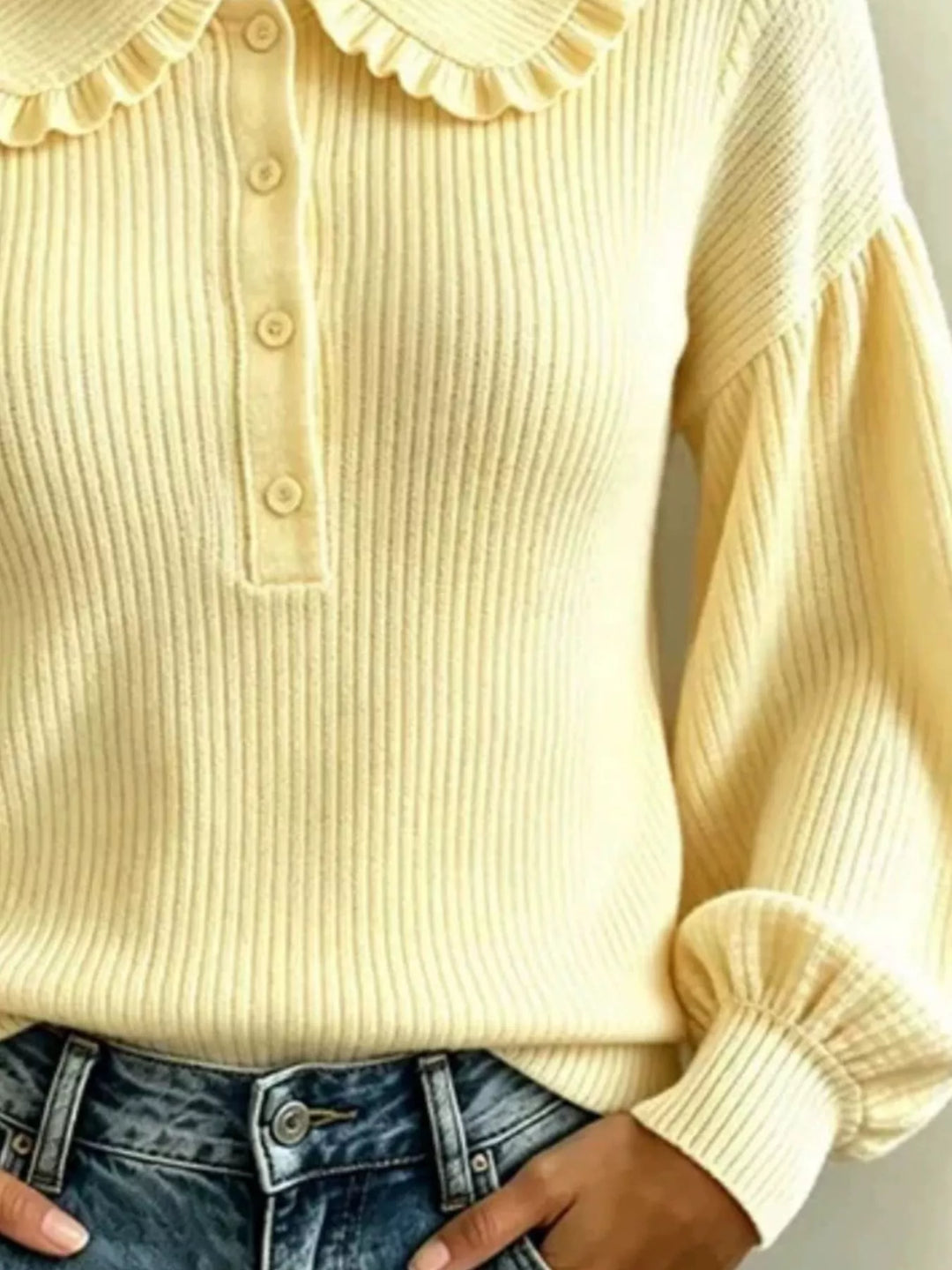 Close-up of light yellow ribbed knit sweater buttons and puff sleeve