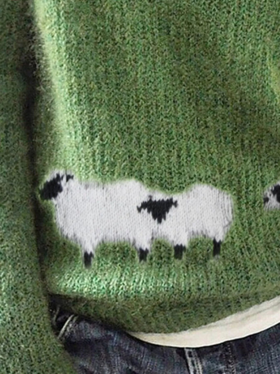 Close-up of the green sweater showing the white sheep motif near the hem
