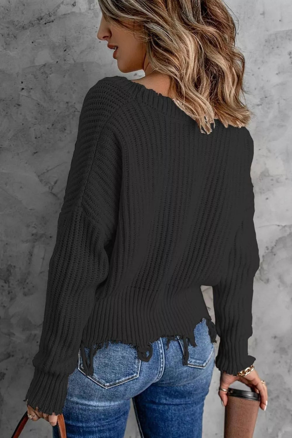 Back angle of the black drop shoulder sweater with frayed bottom edge