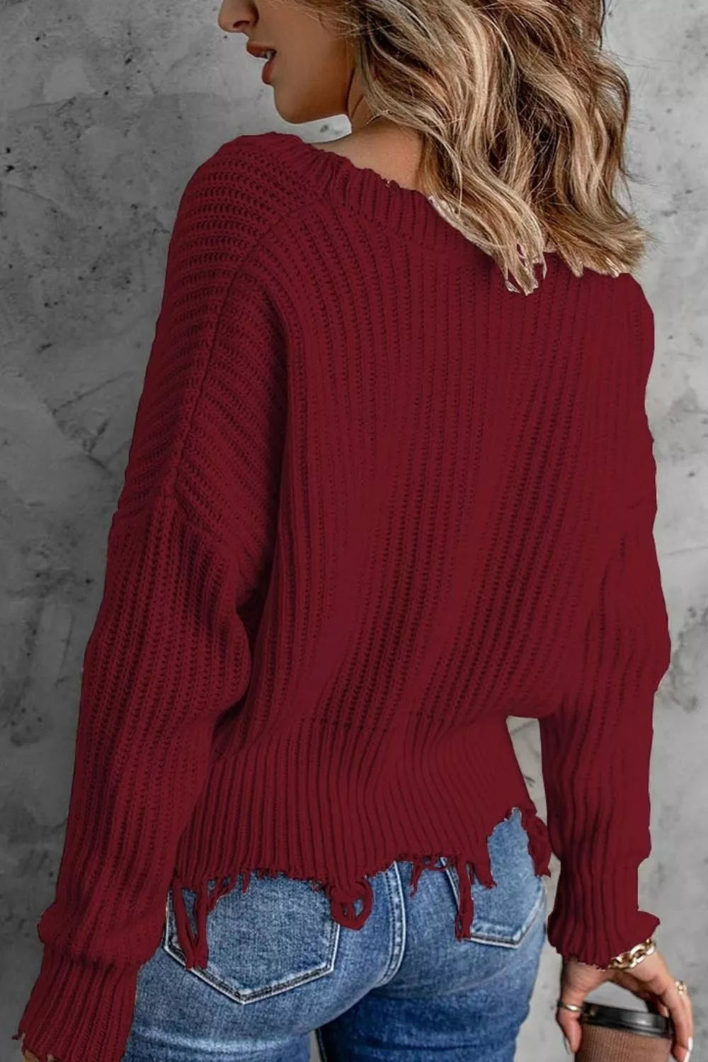 Burgundy drop shoulder sweater back view with frayed edge over jeans