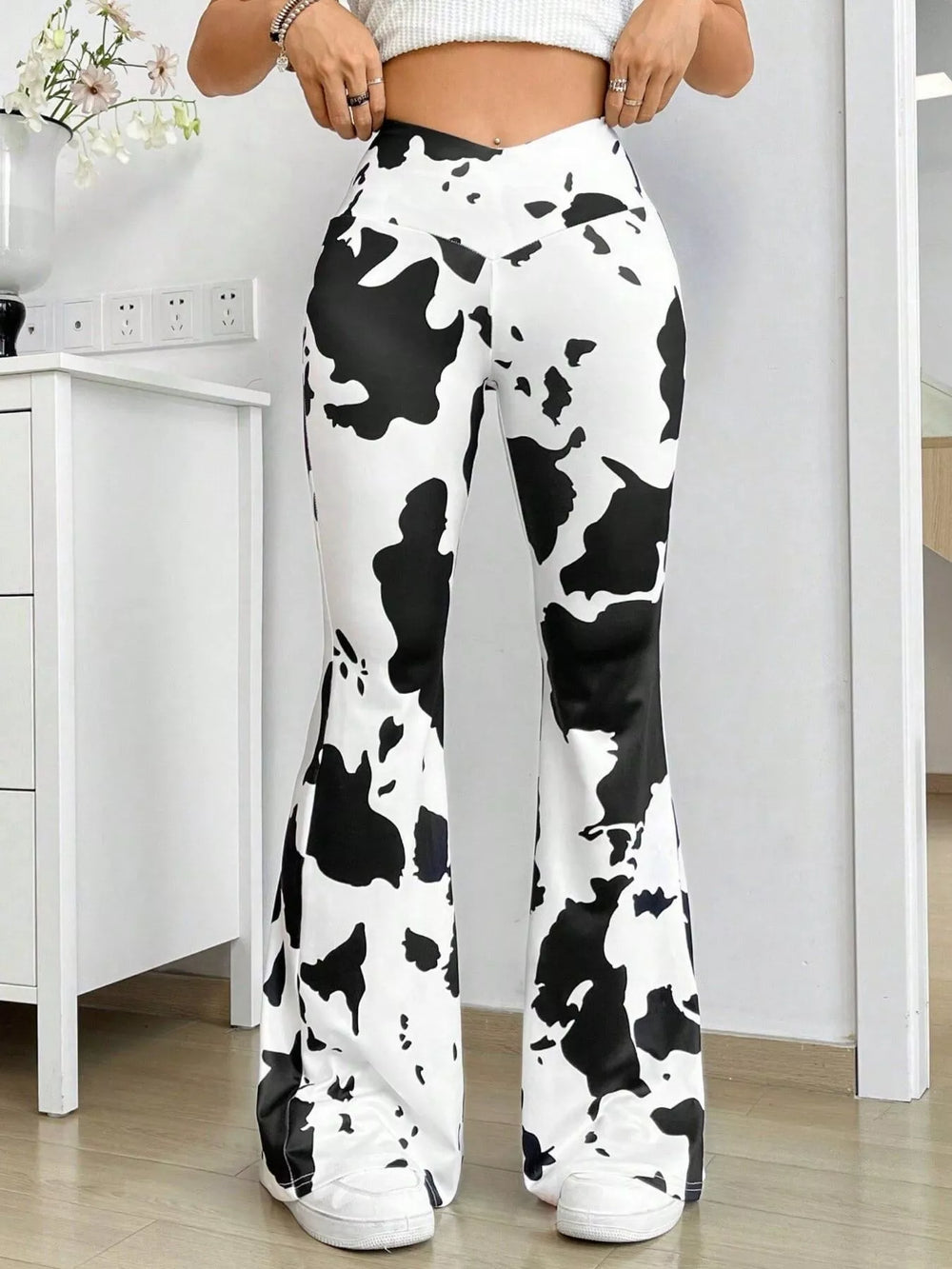 Cow print high waisted flare pants with V waistband, close front view
