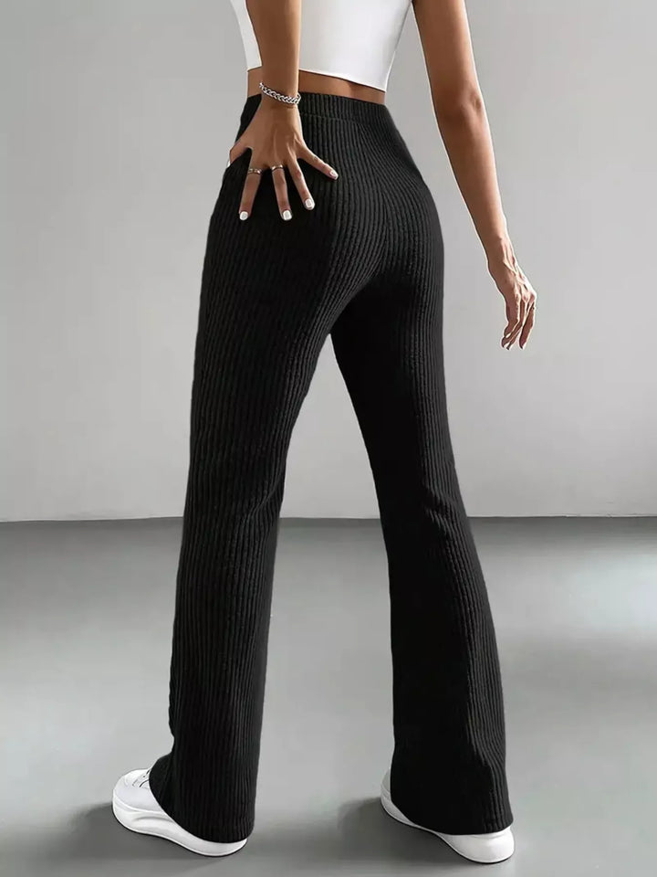 Back view of black ribbed flare pants with hand on hip