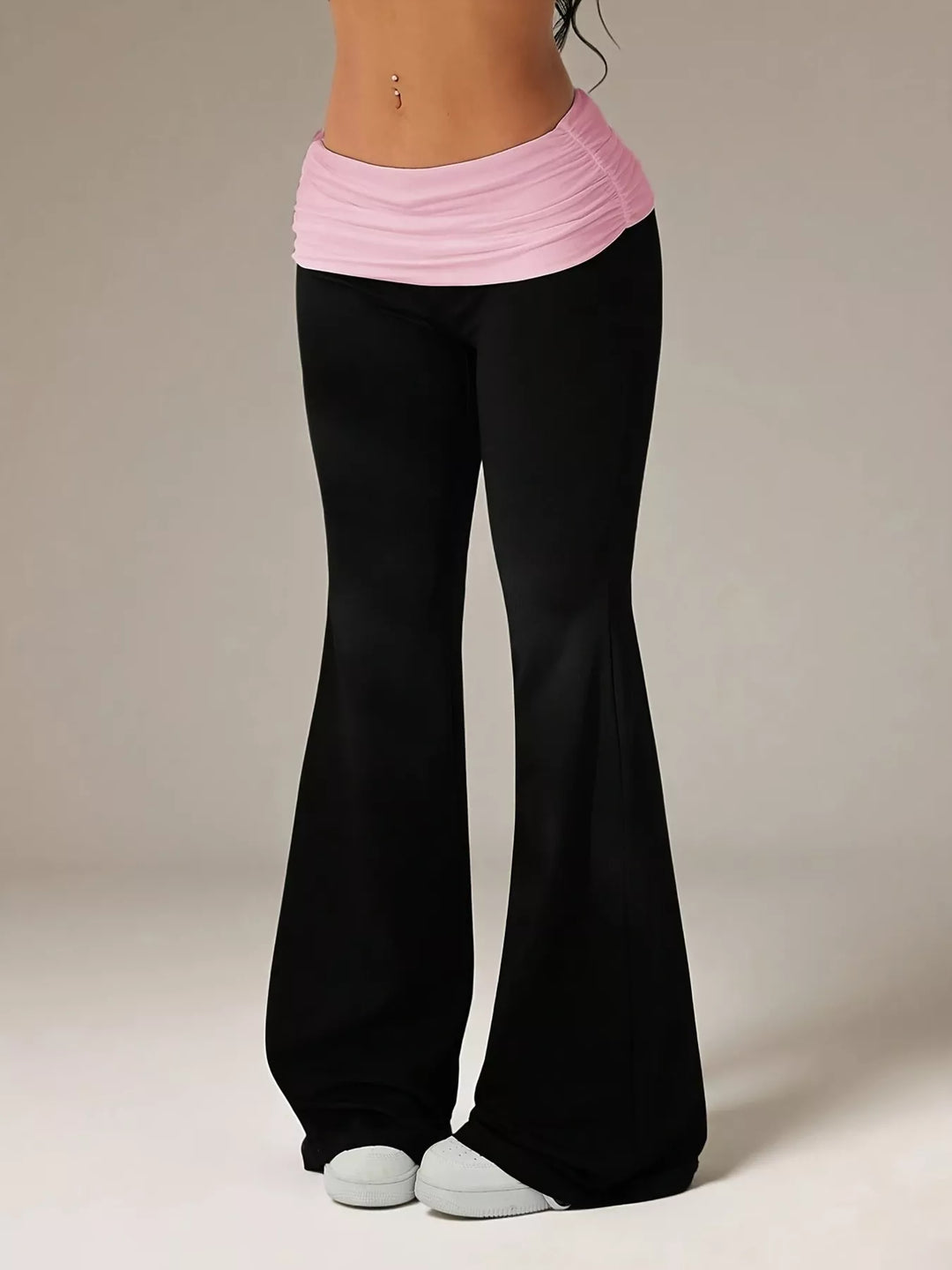 Full-length black and pink waistband flare pants worn with white sneakers
