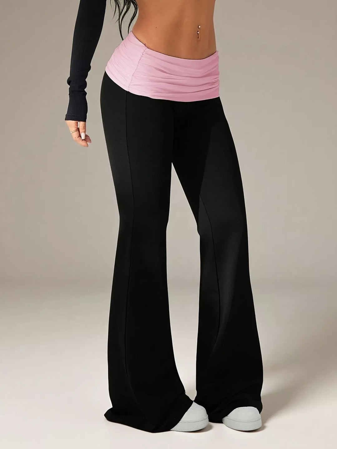 Angled view of the black and pink flare pants with a slim fit through the thigh