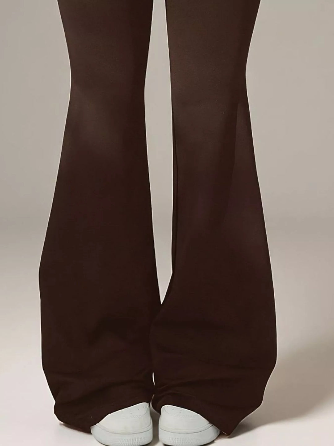 Detail of the brown flare pant hems over white sneakers