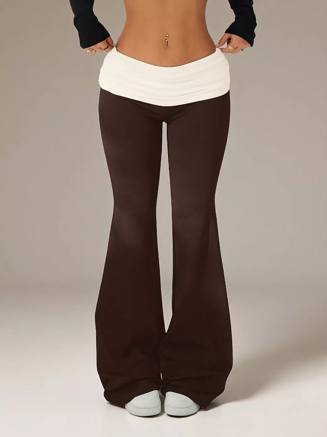 Brown flare pants with a cream fold over waistband, front view with white sneakers